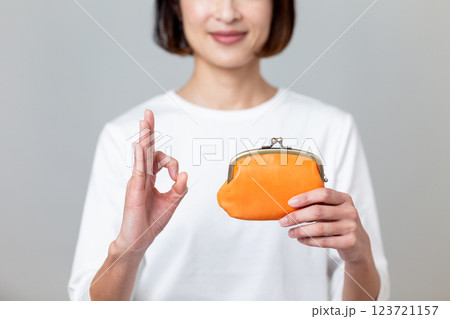 オレンジ色のがま口財布を持って笑顔で丸サインをするミドル女性 123721157