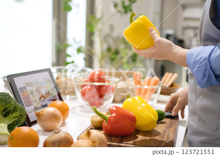 タブレットを見ながら料理をするミドル女性 123721551