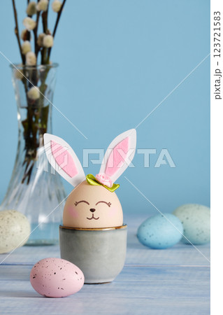 Easter bunny eggs in egg holder on blue background. Multicolored eggs and sprigs of willow. Place for your text 123721583