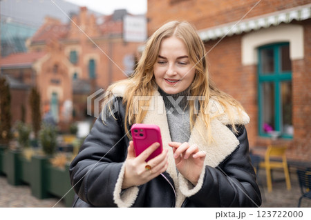 Young stylish 30s woman writes message on smartphone walking on city street. Urban lifestyle concept. Autumn time. Charming female wearing stylish outfit chatting online. High quality photo. Young stylish 30s woman writes message on smartphone walking on city street. Urban lifestyle concept. Autumn time. Charming female wearing stylish outfit chatting online. High quality photo. 123722000