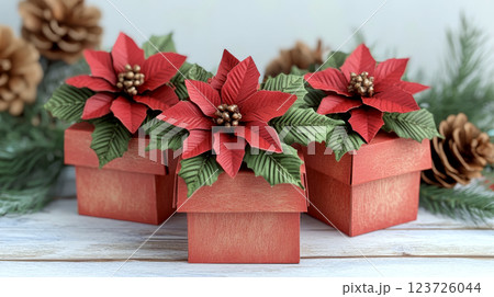 Three decorative red gift boxes with paper poinsettias sit on a wooden surface surrounded by pinecones. Concept of festive holiday decoration. 123726044