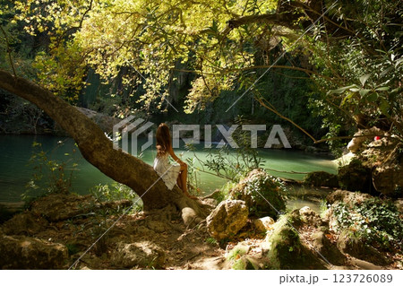 Woman Sitting on Tree by Waterfall Pool Woman Sitting on Tree by Waterfall Pool 123726089