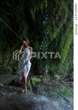Woman Enjoying the Cool Mist of a Waterfall  123726090