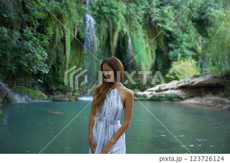 Woman in White Dress Relaxing by a Waterfall and River Woman in White Dress Relaxing by a Waterfall and River 123726124