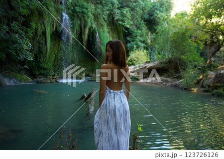 Woman in Elegant Dress Admiring Waterfall and River  123726126