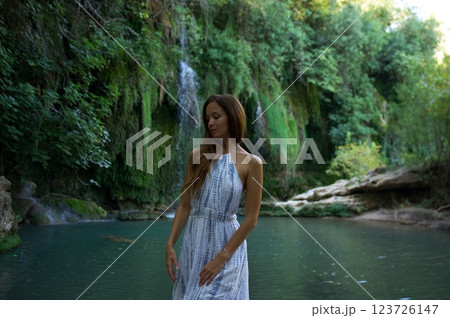 Serene Woman Standing by a Waterfall and River Serene Woman Standing by a Waterfall and River 123726147