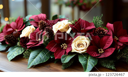 Red and white flowers, pine cones, and greenery are arranged on a wooden surface indoors. Concept of festive floral decoration. 123726467