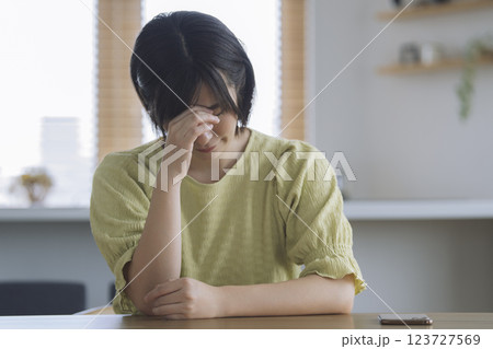 自宅のテーブルで頭を抱えるアラサーの女性 自宅のテーブルで頭を抱えるアラサーの女性 123727569