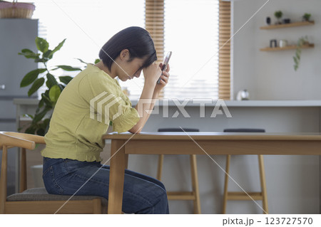 自宅のテーブルで頭を抱えるアラサーの女性　横顔 123727570