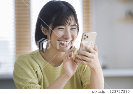 スマートフォンを操作する笑顔のアラサーの女性 スマートフォンを操作する笑顔のアラサーの女性 123727850