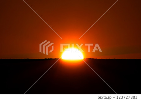 地平線にダイナミックに沈む夕陽のイメージ 123727883