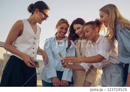 Joyful women share a delightful moment viewing photos in a vibrant setting, celebrating friendship 123728529