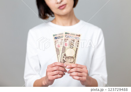 一万円札を持って悩むミドル女性 一万円札を持って悩むミドル女性 123729488