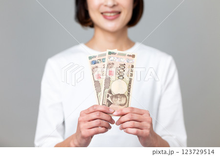 一万円札を持って微笑むミドル女性 123729514