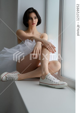 Ballet dancer in lingerie poses gracefully at a studio window Ballet dancer in lingerie poses gracefully at a studio window 123729952