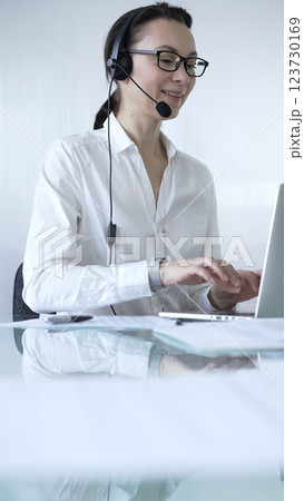 Female secretary wearing headset and working on laptop, providing customer support or online service. Business people concept 123730169