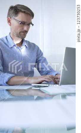 Casual dressed businessman is using a laptop in a contemporary office, with a clean, bright environment that boosts efficiency. Business people concept 123730253