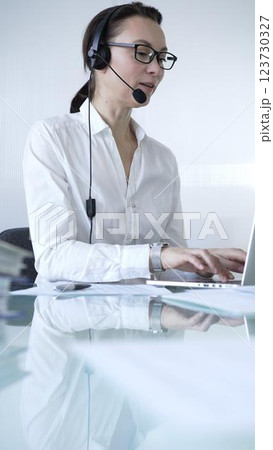 Female secretary wearing headset and working on laptop, providing customer support or online service. Business people concept 123730327