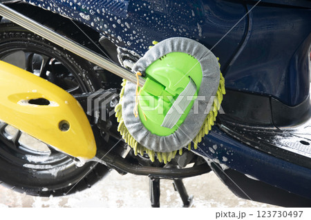 Washing a motorcycle with a brush and a stain remover 123730497