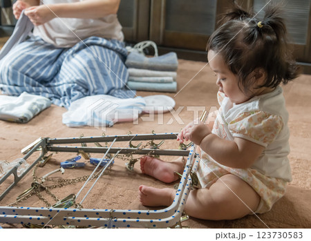 【洗濯ハンガーを触るツインテールの赤ちゃん】 123730583