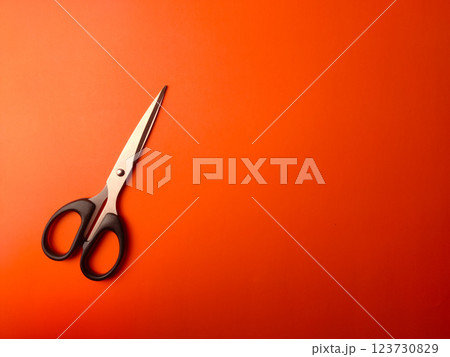 Top view black scissors on an orange background with copy and text space. 123730829