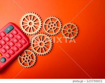 Top view green calculator with wooden gear on a orange background. Business concept. Top view green calculator with wooden gear on a orange background. Business concept. 123730831
