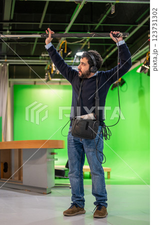 Boom microphone operator testing sound at TV studio. 123731302
