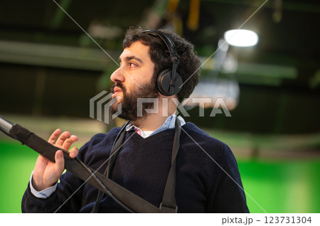 Boom microphone operator testing sound at TV studio. 123731304