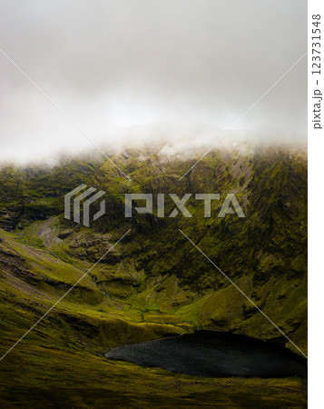 Lush green mountains and dark lake in Ireland under cloudy sky in the afternoon light. 123731548