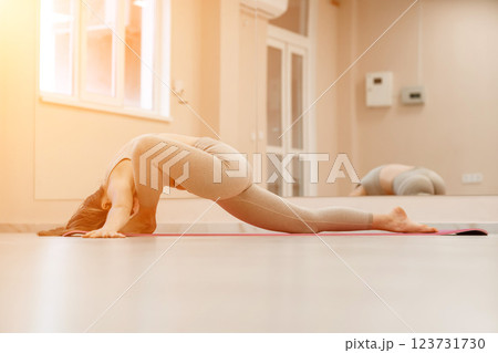 Girl does yoga. Young woman practices asanas on a beige one ton background. Girl does yoga. Young woman practices asanas on a beige one ton background. 123731730