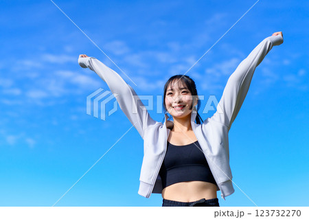 ウォーキングしながら青空に向かってガッツポーズするかっこいい女性　ワークアウト　トリミングアップ 123732270