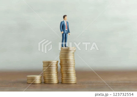 Creative Businessman on Top of Coins Representing Financial Success and Growth Creative Businessman on Top of Coins Representing Financial Success and Growth 123732554