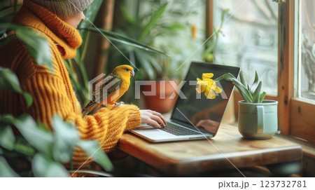 A person working on a laptop in a cozy cafe with a bird perched on the table, Lifestyle of a digital nomad with animal companionship 123732781