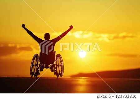 Wheelchair Racer Celebrates Victory with Arms Raised Against a Glowing Sunset 123732810