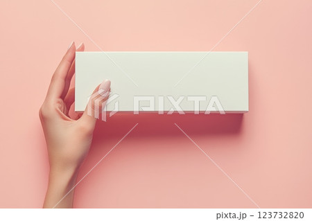 Delicate Hand with Manicured Nails Holding Sleek White Box on Pink Background Delicate Hand with Manicured Nails Holding Sleek White Box on Pink Background 123732820