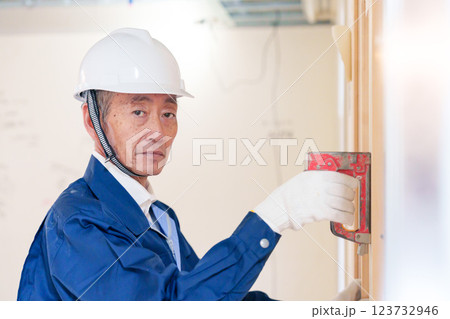 タッカーで建築資材を固定する男性の職人 タッカーで建築資材を固定する男性の職人 123732946