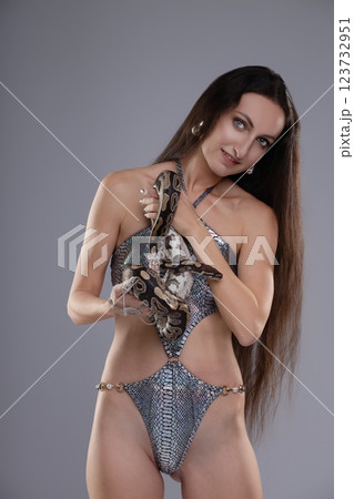 Captivating woman poses with snake, showcasing beauty and elegance in lingerie 123732951