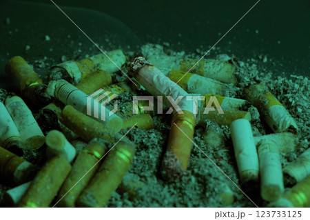 closeup, Cigarette butt on dark green background. cigarette butt. cigarette; closeup, Cigarette butt on dark green background. cigarette butt. cigarette; 123733125