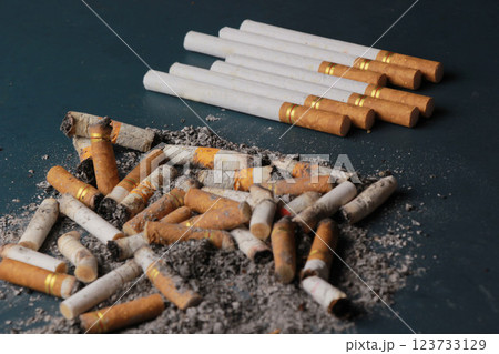 Dirty cigarette butts with stack of cigarettes, plain turquoise isolated. blur. Dirty cigarette butts with stack of cigarettes, plain turquoise isolated. blur. 123733129
