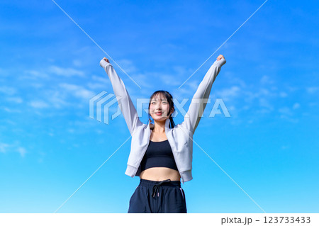 ウォーキングしながら青空に向かってガッツポーズするかっこいい女性 ワークアウト トリミングアップ ウォーキングしながら青空に向かってガッツポーズするかっこいい女性 ワークアウト トリミングアップ 123733433