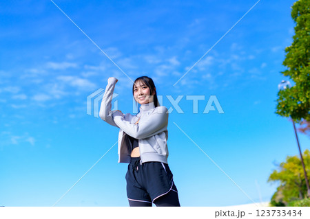 ウォーキングしながら青空に向かってガッツポーズするかっこいい女性　ワークアウト　散歩　有酸素運動　 123733434