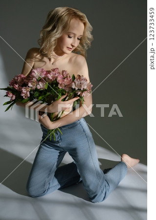 Model holding pink flowers while posing gracefully indoors 123733459