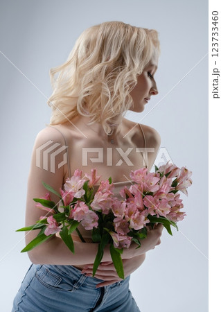 Model with flowers poses gracefully against a plain background 123733460