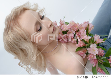 Model poses gracefully with pink flowers in a studio setting Model poses gracefully with pink flowers in a studio setting 123733462