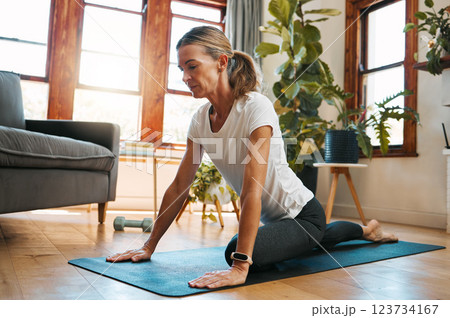 Woman, yoga and pigeon pose stretching in house or home living room for relax exercise, training and workout in Germany lockdown. Zen, calm and mature peace yogi in mind wellness and fitness for hips 123734167