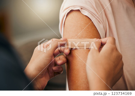 Covid, vaccine and plaster with a doctor and patient consulting in an appointment or checkup at home. Nurse, healthcare and trust with a health professional using a bandaid on an arm after medication 123734169