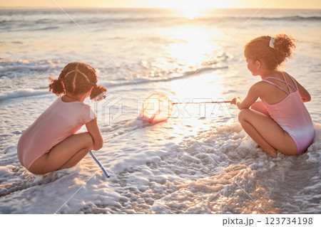 Children, girls and fishing with nets at the beach in playful fun on summer vacation in the outdoors. Little girl siblings playing and exploring the ocean in low tide to catch fish in the sunset Children, girls and fishing with nets at the beach in playful fun on summer vacation in the outdoors. Little girl siblings playing and exploring the ocean in low tide to catch fish in the sunset 123734198