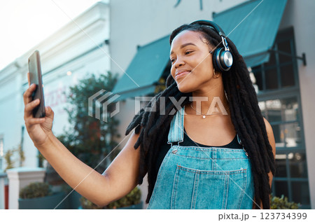 Phone, selfie and happy black woman in the city street with headphones listening to music, podcast or radio. Happiness, technology and african girl on a walk in the urban road on a smartphone. Phone, selfie and happy black woman in the city street with headphones listening to music, podcast or radio. Happiness, technology and african girl on a walk in the urban road on a smartphone. 123734399