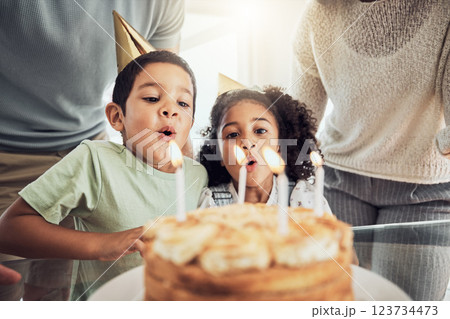 Children, birthday cake and blowing candles in celebration event, fun party or Brazilian family social reunion with parents. Boy, girl or kids with sweet dessert food in house or home with mom or dad 123734473