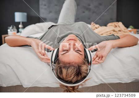 Sleep music, bed and woman listening to audio podcast with headphones in the bedroom of her house. Sleeping girl streaming calm radio sound for peace, relax and content mind with wifi in home 123734509